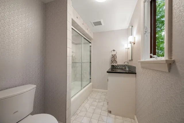 a bathroom with a granite countertop sink a toilet a mirror and window