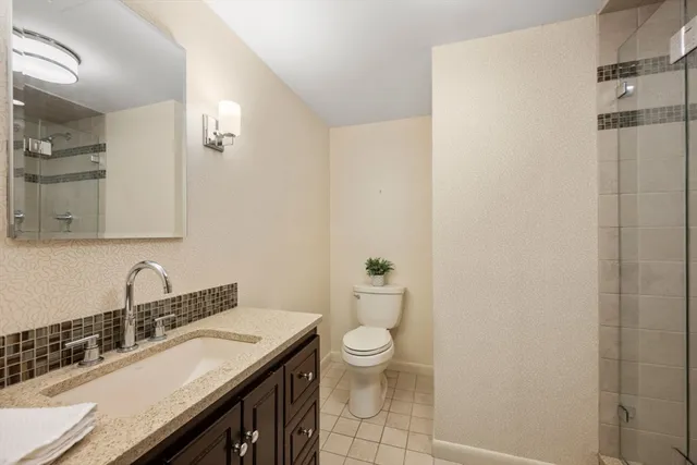 a bathroom with a granite countertop sink a toilet and a mirror