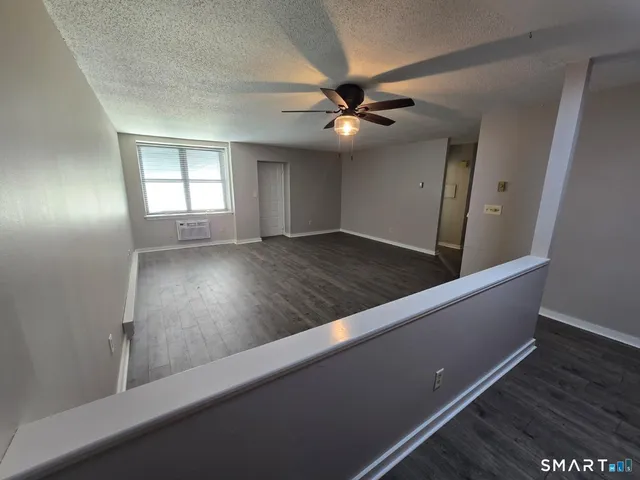 an empty room with wooden floor fan and windows
