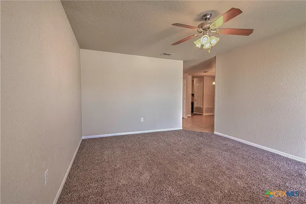 a view of an empty room with a chandelier fan