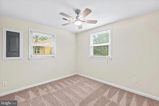 a view of an empty room with window and a ceiling fan