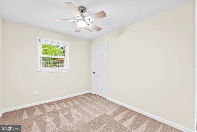 an empty room with a chandelier fan and windows
