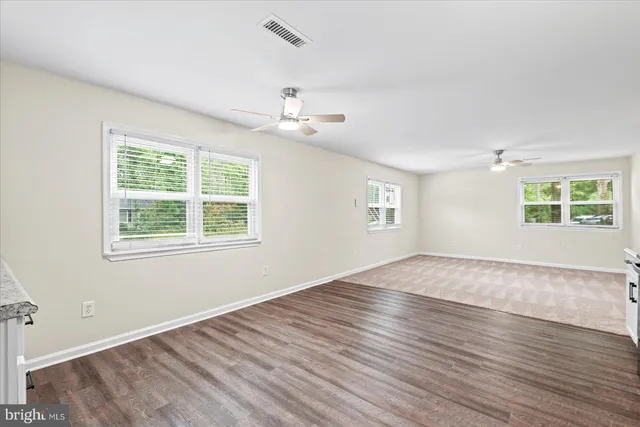 an empty room with wooden floor chandelier and windows