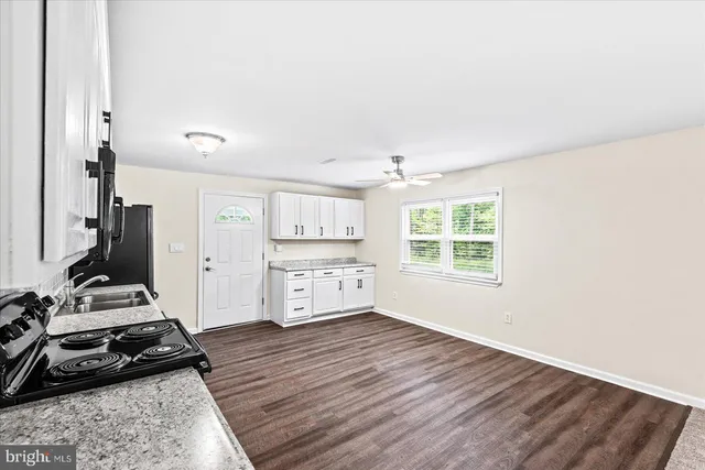 a room with a hardwood floor a ceiling fan and windows