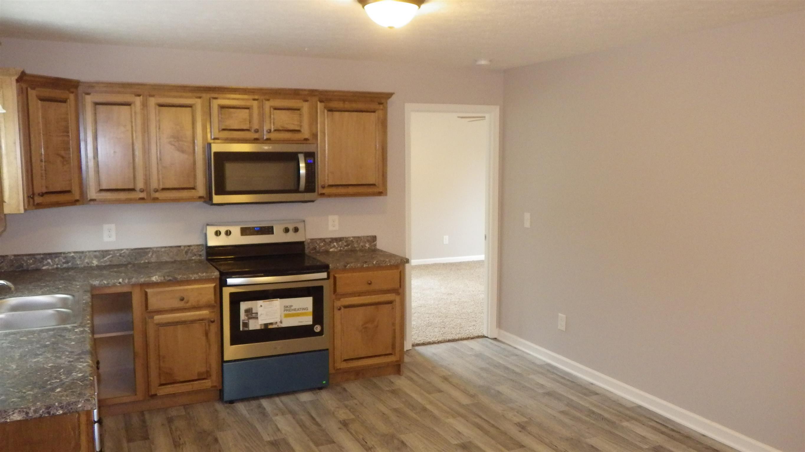 1211 East Ab Wade Road Portland, TN 37148 - Photo 17 of 30 a kitchen with wooden floor and steel appliances