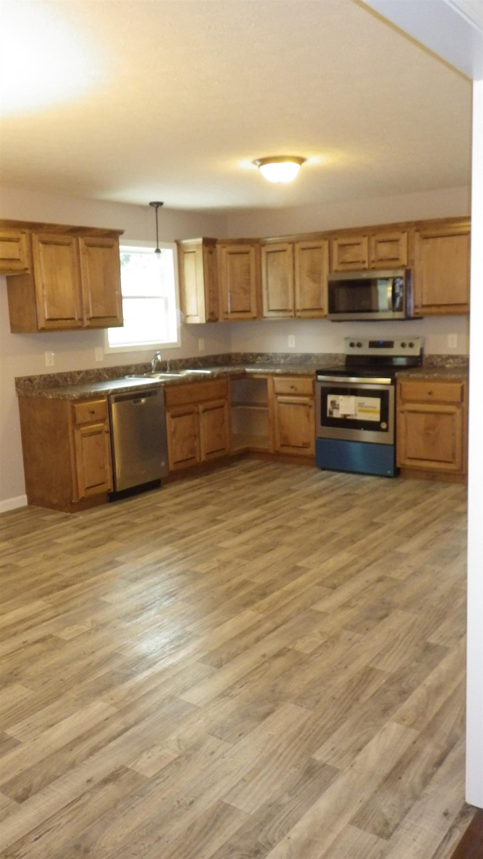 1211 East Ab Wade Road Portland, TN 37148 - Photo 21 of 30 a kitchen with stainless steel appliances granite countertop a stove a sink and a microwave