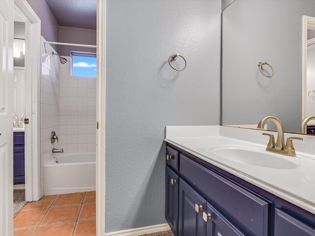 19910 Kennemer Drive Pflugerville, TX 78660 - Photo 16 of 21 a bathroom with a granite countertop sink a mirror and shower