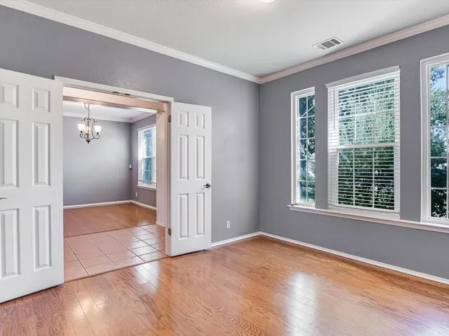 a view of empty room with wooden floor and fan