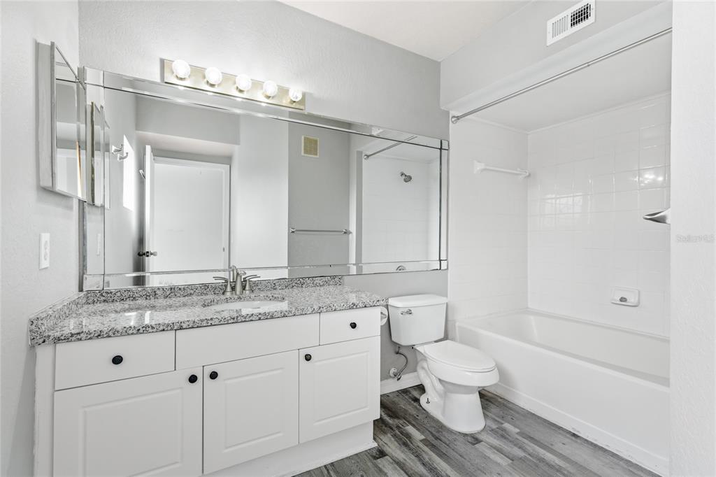5122 Northridge Road, Unit 307 Sarasota, FL 34238 - Photo 20 of 51 a bathroom with a granite countertop sink toilet a large mirror a vanity and shower