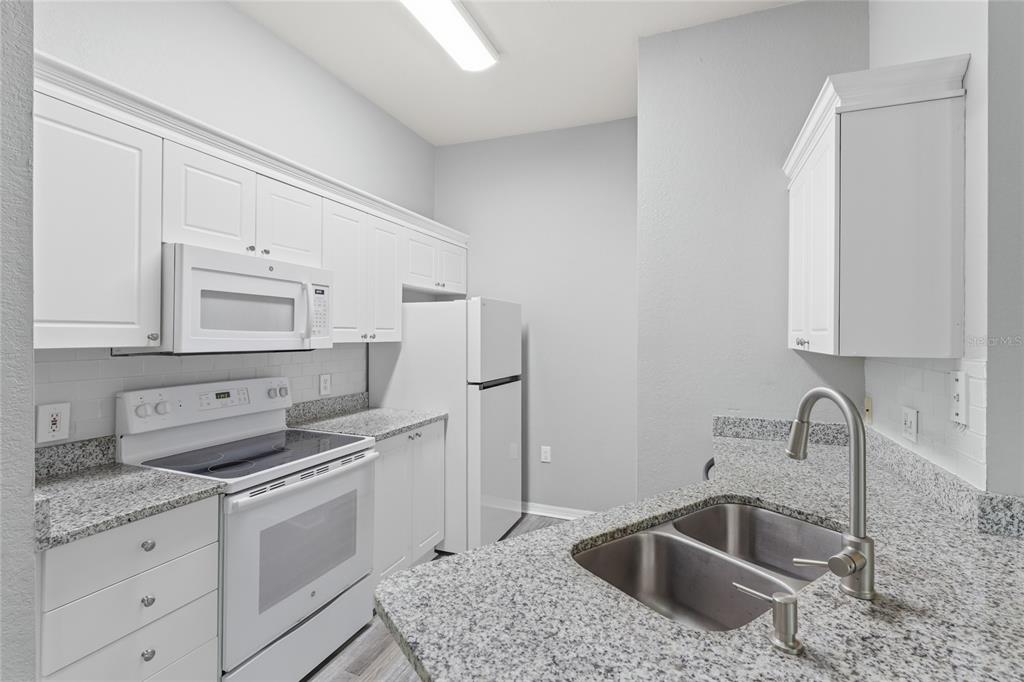 5122 Northridge Road, Unit 307 Sarasota, FL 34238 - Photo 9 of 51 a kitchen with stainless steel appliances granite countertop a sink stove and refrigerator