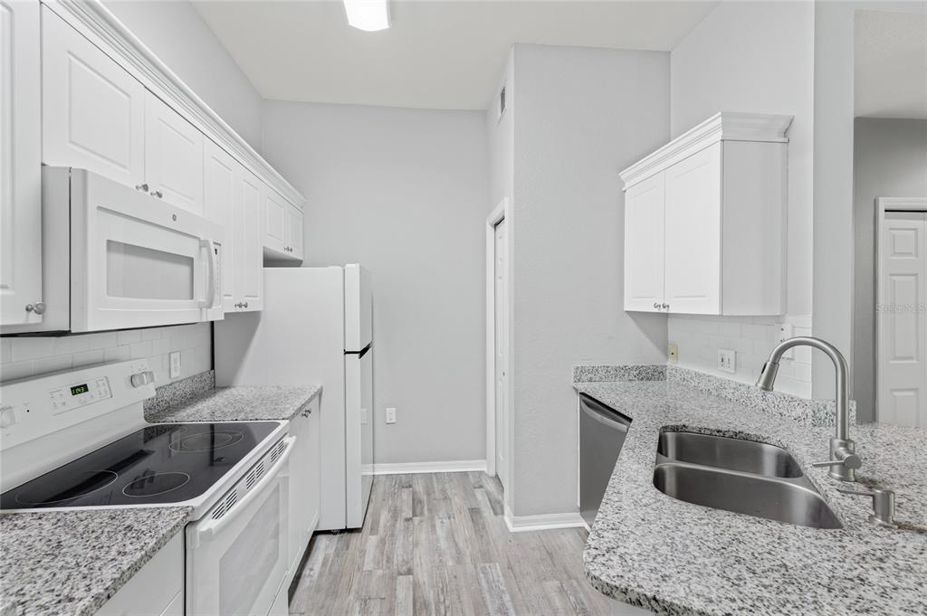 5122 Northridge Road, Unit 307 Sarasota, FL 34238 - Photo 10 of 51 a kitchen with granite countertop a sink stove and refrigerator