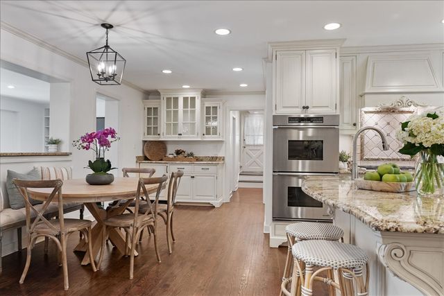 a kitchen with stainless steel appliances kitchen island granite countertop a dining table chairs stove refrigerator and cabinets