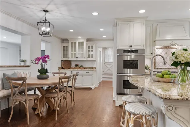 a kitchen with stainless steel appliances kitchen island granite countertop a dining table chairs stove refrigerator and cabinets