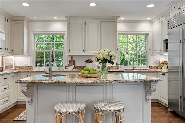 a kitchen with kitchen island granite countertop a sink and a white wooden cabinets