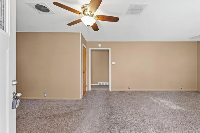 an empty room with a ceiling fan and a window