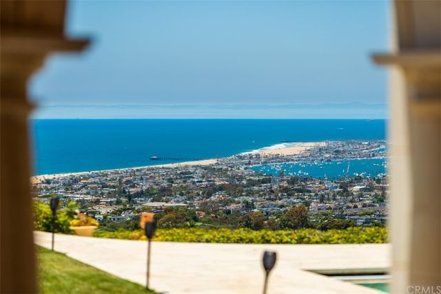 a view of a dining room with furniture a chandelier and large windows