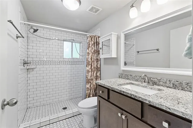 a bathroom with a granite countertop sink toilet and shower