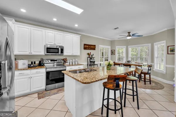 a kitchen with stainless steel appliances granite countertop a stove a sink dishwasher a dining table and chairs with wooden floor