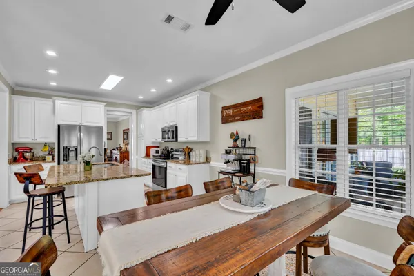 a kitchen with stainless steel appliances kitchen island granite countertop a dining table chairs and granite counter tops