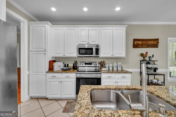 a kitchen with stainless steel appliances granite countertop a stove top oven a sink dishwasher and white cabinets