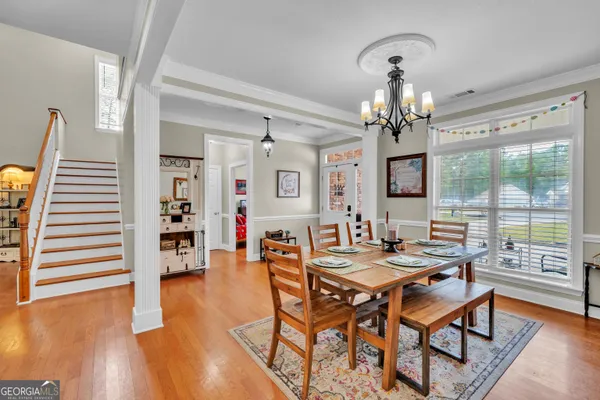 a dining room with wooden floor a chandelier a wooden table and chairs