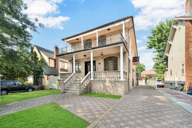 a front view of a house with a garden and bench