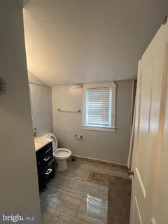 a bathroom with a granite countertop toilet a sink and a mirror