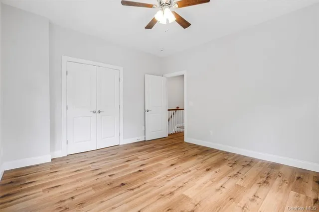 a view of empty room with wooden floor and ceiling fan