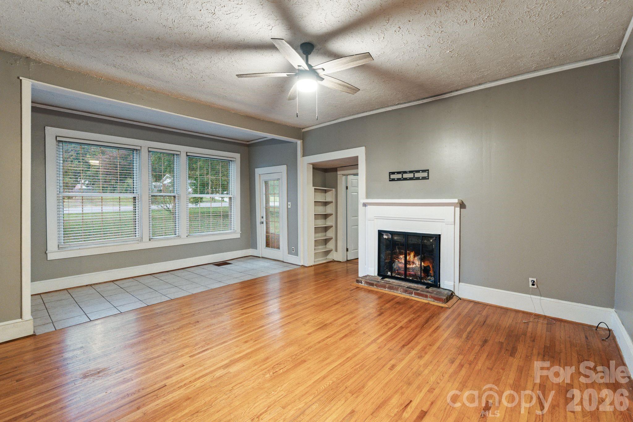 6921 Harmony Grove Road Nebo, NC 28761 - Photo 4 of 21 a view of an empty room with wooden floor fireplace and a window