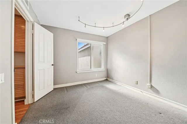 an empty room with wooden floor chandelier fan and windows