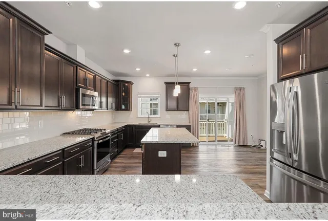 a kitchen with stainless steel appliances granite countertop a sink a stove and a refrigerator