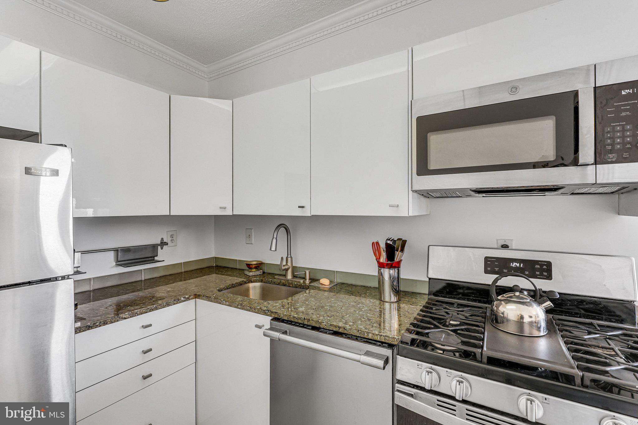 1245 4th Street Southwest, Unit E711 Washington, DC 20024 - Photo 9 of 33 a kitchen with stainless steel appliances granite countertop a sink stove top oven and cabinets