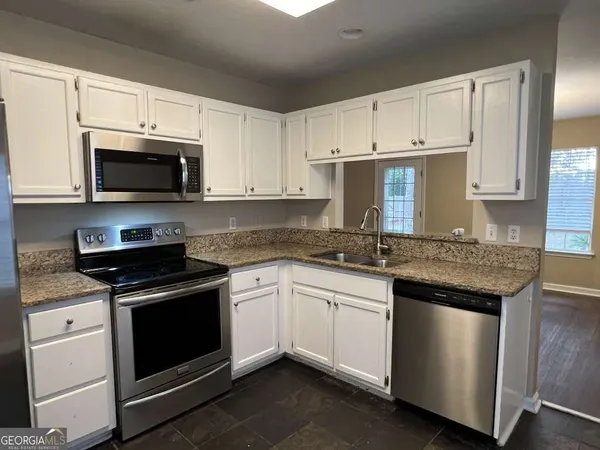 a kitchen with granite countertop white cabinets and stainless steel appliances