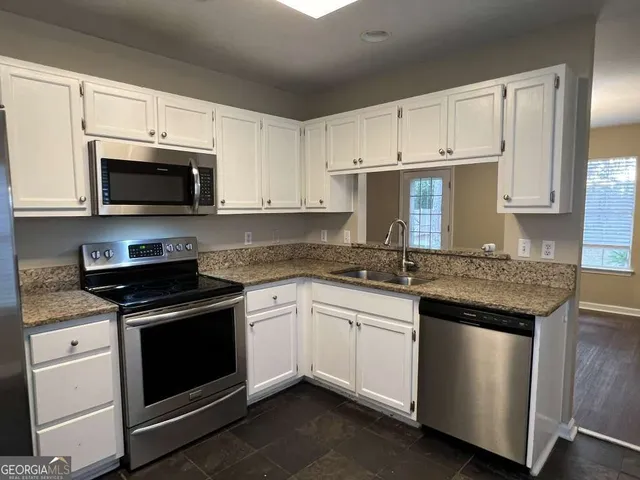 a kitchen with granite countertop white cabinets and stainless steel appliances
