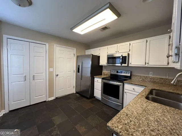 a kitchen with granite countertop a refrigerator and a stove top oven