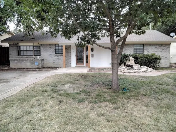 a front view of a house with a yard and large tree