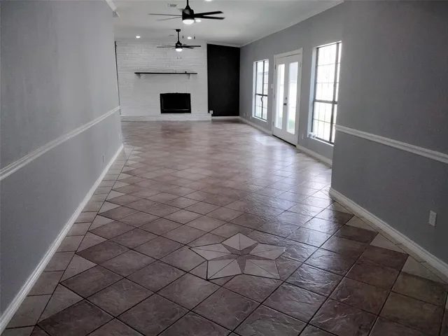 an empty room with windows and fireplace