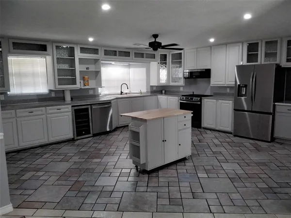 a kitchen with stainless steel appliances granite countertop a sink a stove a refrigerator cabinets and window