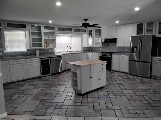 a kitchen with stainless steel appliances granite countertop a sink a stove a refrigerator cabinets and window