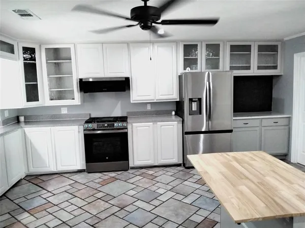 a kitchen with stainless steel appliances kitchen island granite countertop a refrigerator and a stove top oven