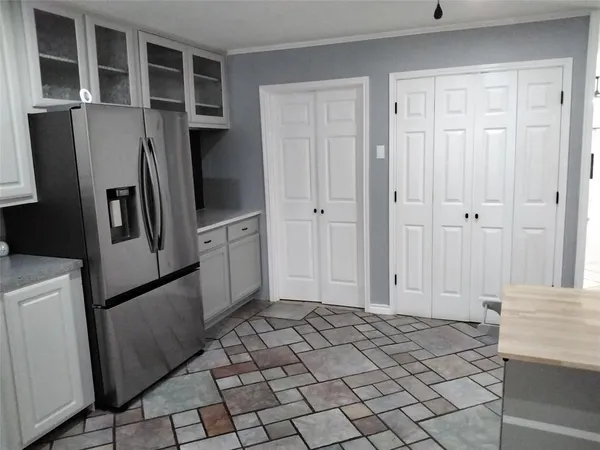 a view of a refrigerator in kitchen and an empty room with wooden floor