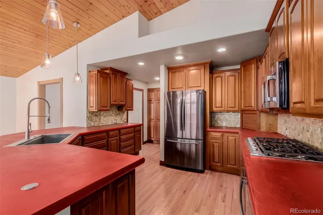 a kitchen with granite countertop a refrigerator and a stove top oven