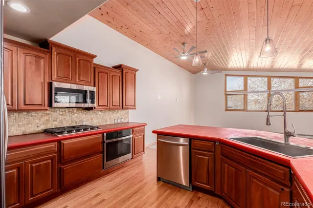 a kitchen with stainless steel appliances granite countertop wooden cabinets a sink and dishwasher a oven with wooden floors