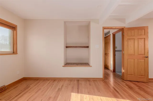 an empty room with wooden floor and a window