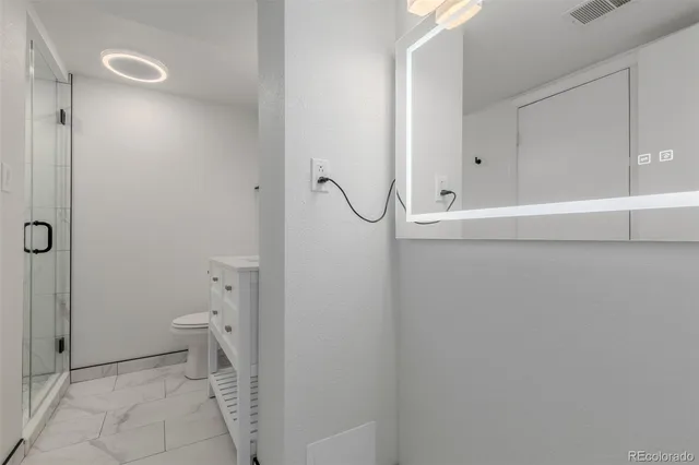 a bathroom with a granite countertop toilet and a shower