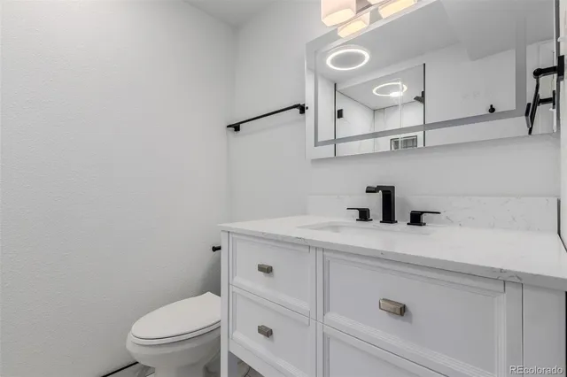 a bathroom with a granite countertop sink a toilet and a mirror