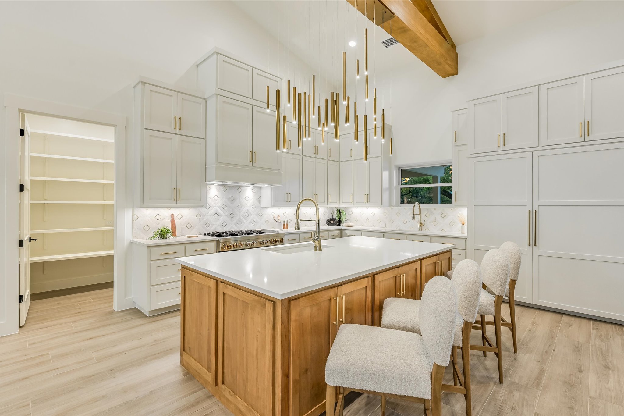 410 Shady Tree Drive Georgetown, TX 78633 - Photo 10 of 40 Two tone kitchen featuring dual tone cabinets, a kitchen island with sink, light wood finished floors, decorative backsplash, and a kitchen breakfast bar