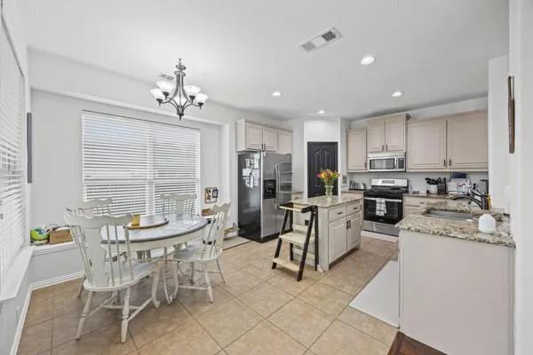 a kitchen with a refrigerator a stove a dining table and chairs