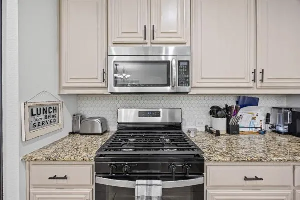 a kitchen with granite countertop white cabinets and stainless steel appliances