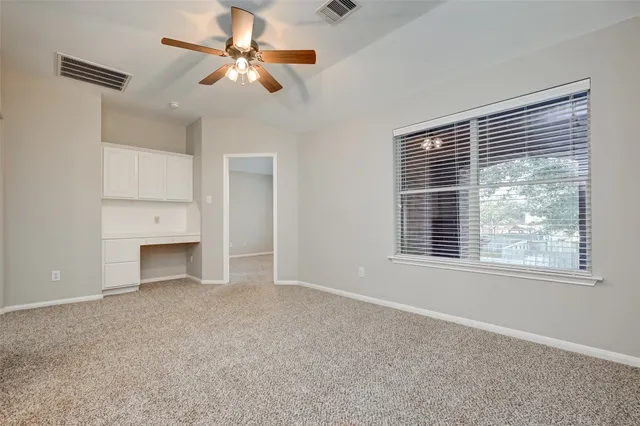 a view of an empty room with a window and a kitchen